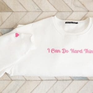 A white sweatshirt with pink lettering on it.