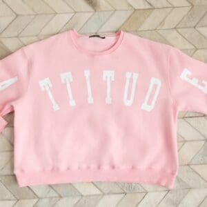A pink sweatshirt with the word " titud " written on it.